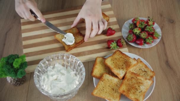 チーズをトーストした白いパンの上にのせる女性の手 ストロベリーサンドイッチの調理プロセス ヘルシーな食べ物だトップ表示 — ストック動画