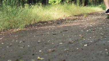 Yakın erkek bacaklar yaz parkında gemide binmek başlar. Park açık kaykay üzerinde patenci çocuk binmek. Turuncu paten ayak ayakkabı giymek, paten kurulu güverte.