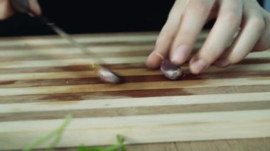 Ahşap masa üst arka plan üzerinde sarımsak karanfil deri soyma. Kadın elleri yemek hazırlar. Elleriyle soyulmuş sarımsak, yakın.