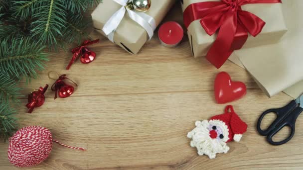 女性の手は 赤と白のツインでクラフト紙に包まれたクリスマスの贈り物を与える 木製のテーブルの上からの眺め フラットレイアウト トップビュー — ストック動画