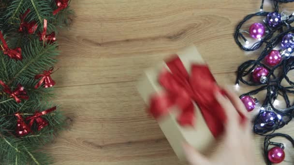 軽い木製の平らな横にギフトボックスをつかむ手 クリスマス トップビュー — ストック動画