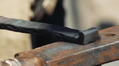 Smith örs üzerinde kanca kırmızı sıcak demir oluşturan. Demirci dövme örs üzerinde çekiç sıcak metal yener. Smithy sokakta. Yakın çekim.