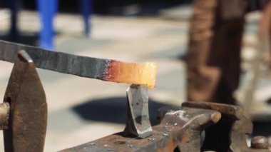 Anvil'de Bir Demirci Metal Çubuğu Kesmek için Hardy Kesme Aracı kullanıyor. Demirci, kıvılcım havai fişeklerle demircide erimiş metali elle dövülerek