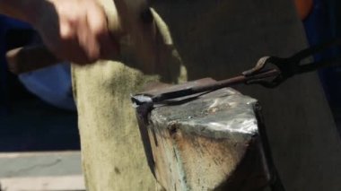 Demirci el ile bir çekiç, bir örs ve forseps yardımıyla metalden bir gül döver. Close.