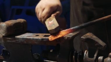 Demirci metali ölçekten elle fırçalar. Demirci, kıvılcım havai fişeklerle demircide erimiş metali elle dövülerek.