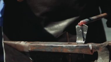 Anvil'de Bir Demirci Metal Çubuğu Kesmek için Hardy Kesme Aracı kullanıyor. Demirci, kıvılcım havai fişeklerle demircide erimiş metali elle dövülerek