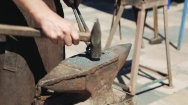 Demirci elle metalden bir kalp dövüldü. Çekiç ve maşalarla metal bir kalbin şeklini düzeltir..