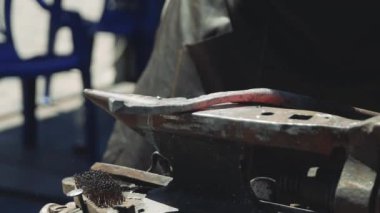 Smith örs üzerinde kanca kırmızı sıcak demir oluşturan. Demirci dövme örs üzerinde çekiç sıcak metal yener. Smithy sokakta. Yavaş çekim, odak changin, yakın çekim.