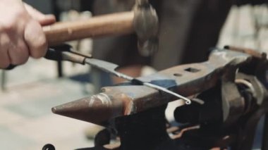 Bir demirci çekiç ve maşa kullanarak sıcak bir metal bir bıçak sapı yapar. Demirci dövme örs üzerinde çekiç sıcak metal yener. Sokakta gebe. Close. Sıcak metal, demir.