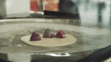 Yemek pişirmek sokakta dondurma yuvarlanmış. Dondurma satıcısı çilek ile dondurma kısmını yapar. Soğuk bir tavada dondurma