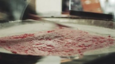 Yemek pişirmek sokakta dondurma yuvarlanmış. Dondurma satıcısı çilek ile dondurma kısmını yapar. Soğuk bir tavada dondurma