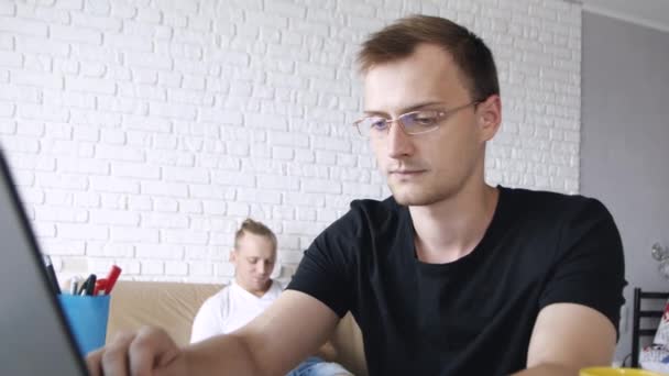 年轻的集中的白种人男子正在敲打笔记本电脑 喝着黄色的杯子 概念自由职业者在 — 图库视频影像
