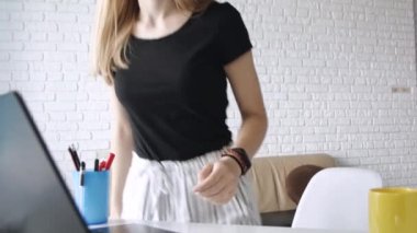 Genç güzel beyaz kız ısınma elleri yapar ve ev ofisinde bir dizüstü bilgisayar da çalışmaya başlar.