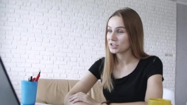 Dizüstü bilgisayarda görüntülü görüşme olan ve alınan haberlerden şok eyleen genç beyaz beyaz kadının yakın portresi. 