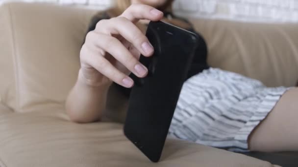 Mujer Nerviosa Sentada Sofá Gira Teléfono Negro Sus Manos Concepto — Vídeos de Stock