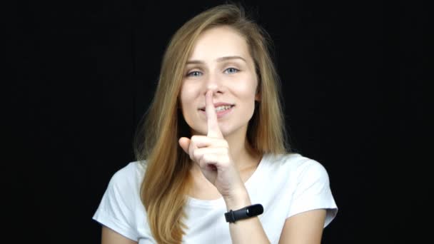 英俊的年轻白人妇女做Hush标志用手指在嘴唇上 看着相机 黑色背景上的沉默手势 安静的标志特写肖像 情感的概念 — 图库视频影像
