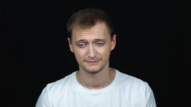 Siyah arka plandaki kameraya bakan mutsuz beyaz adamın portresi. Üzgün gençler ve olumsuz duygular kavramı.