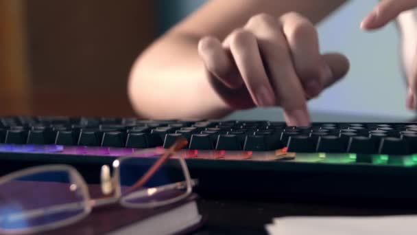 テーブルの自宅で多色の照明とコンピュータのキーボードに入力する女性の手のクローズアップショット 極端なクローズアップビデオ — ストック動画