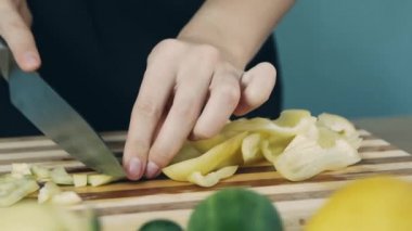 Bıçak sarı biberi keser. Ahşap kesme tahtası üzerine tatlı biber dilimleme. Yakın tatlı biber kesti. Sağlıklı beslenme konsepti. Diyet gıda. 