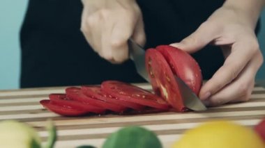 Mutfak bıçağı slayt kullanarak kadınların çekim ellerini kapatın pişirme için hazırlanıyor ahşap kesme tahtası üzerinde taze domates kesti. Domates halkası. Salata için sebze kes. Sağlıklı gıda.