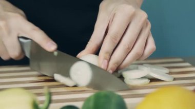 Aşçı tahta bir doğrama tahtasıüzerinde soğan kesme. Kadın el masada beyaz soğan kesme yakın. Soğan halkası. Salata için sebze kes. Sağlıklı gıda.