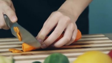 Havuç keskin mutfak bıçağı kullanılarak ahşap doğrama tahtası üzerinde dilimlenmiş ediliyor. Yakından kapatın. Havuç halkası. Salata için sebze kes. Sağlıklı gıda.