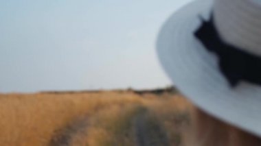 Güzel gülümseme alanında yürüyüş ile beyaz elbise büyüleyici ilham kız portre. Çayır şapkalı çekici genç kadın etrafında dönüm çayırda yürüyor. Yakın çekim, yavaş hareket. 