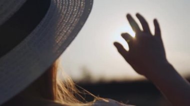 Kadın el gün batımı üzerine alan güneş dokunur. Kız yakın güneş doğaya karşı gökyüzünde yükseltilmiş el. Kadının eli güneş ışınlarına dokunmadan, yaz zamanı, parmaklarıyla güneşin parlaması. Turizm seyahat