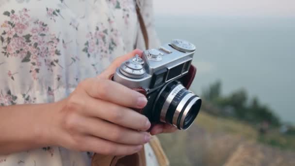 若い美しい写真家の女性は 海の背景にヴィンテージカメラでフィールドに立っています レトロなカメラで写真を撮る準備 — ストック動画