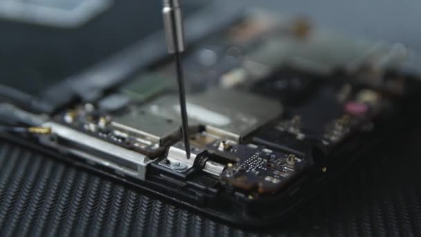 Gros plan montrant le processus de réparation du téléphone cellulaire. Mains de réparateur sortant les vis avec un tournevis. Les composants internes d'un smartphone. Téléphone cellulaire démonté . 