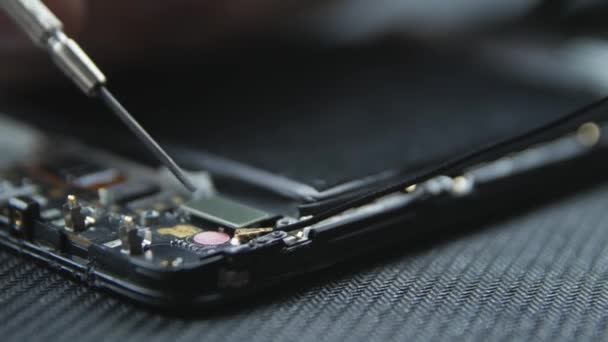 携帯電話の修理の過程を示すクローズアップショット ドライバーでネジを出す修理工の手 スマートフォンの内部コンポーネント 分解された携帯電話 スペースのコピー — ストック動画