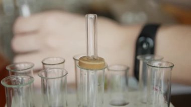 Bir üniversite / okul laboratuvarında, pipet li bir öğrenci test tüplerinde bir sıvıanaliz eder. Kavram: araştırma, biyokimya, çalışma, kimyager