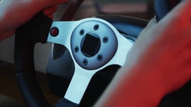Bir yarış simülatörü direksiyonuna genç bir oyuncu nun ellerini yakın çekim ve düğmeleri basmak. Genç oyuncu bir tekerlek ile araba yarışı video oyunu zevk. Bilgisayar simülasyonu.