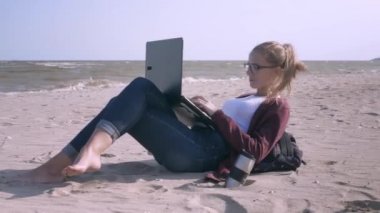 Genç, yakışıklı kadın bir dizüstü bilgisayar üzerinde çalışıyor ve batan güneşin de sahilde kahve içiyor. Genç işadamı gün batımında bir deniz plajında çalışıyor. Bir serbest deniz kıyısında çalışır.
