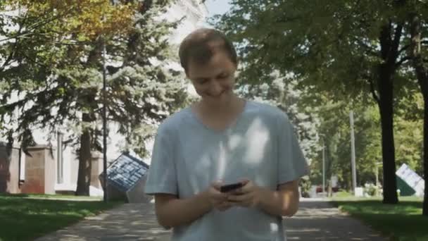 Feliz Jovem Caucasiano Atraente Homem Usar Smartphone Andando Parque Verão — Vídeo de Stock