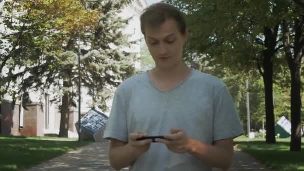 Feliz Jovem Caucasiano Atraente Homem Usar Smartphone Andando Parque Verão — Vídeo de Stock