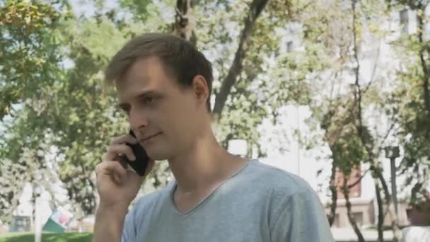 Молодий Привабливий Білий Чоловік Розмовляє Телефону Ходячи Літньому Парку Сонячний — стокове відео