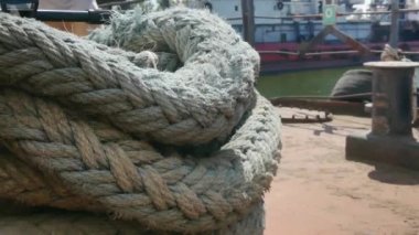 Yakın çekim deniz düğümü halatı tekne veya gemi, tekne demirleme halatı kazık etrafında bağlı. Gemide deniz ipi var. Gemi limandan ayrılıyor. Deniz feneri. Demirleme ipi. Limanda gemi. 
