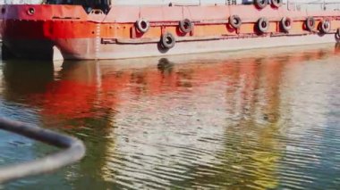 Ticaret gemisindeki dalgalanmaların ve dalgaların yansıması. Gün batımında geminin panosunda güneş ışığı su yansımaları. Sakinlik ve huzur, yakın çekim. 