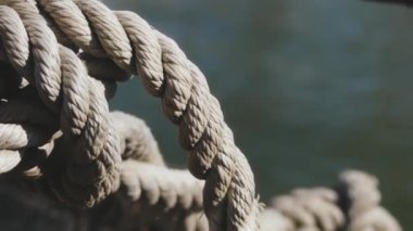 Yakın çekim deniz düğümü halatı tekne veya gemi, tekne demirleme halatı kazık etrafında bağlı. Gemide deniz ipi var. Gemi limandan ayrılıyor. Deniz feneri. Demirleme ipi. Limanda gemi. 