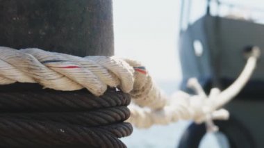 Yakın çekim deniz düğümü halatı tekne veya gemi, tekne demirleme halatı kazık etrafında bağlı. Gemide deniz ipi var. Gemi limandan ayrılıyor. Deniz feneri. Demirleme ipi. Limanda gemi. 