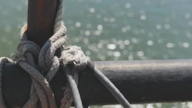 Yakın çekim deniz düğümü halatı tekne veya gemi, tekne demirleme halatı kazık etrafında bağlı. Gemide deniz ipi var. Gemi limandan ayrılıyor. Deniz feneri. Demirleme ipi. Limanda gemi. 