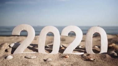 2020 yılı, deniz kıyısındaki taşlar ve kabuklar arasında kum üzerinde sayılar. Yeni Yıl 2020 kavramı geliyor - bir kum plajda rakamlar. Yeni yıl tatili. Close.