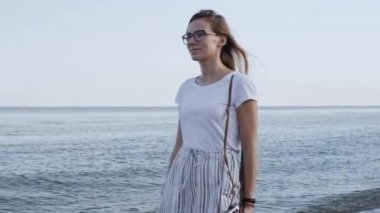 Beyaz şort genç güzel kadın bir gün batımı arka planda eski retro kamera ile sahil yürüyüş. Yakından kapatın. Tasasız kadın plajda doğa ve güneş ışığı zevk.