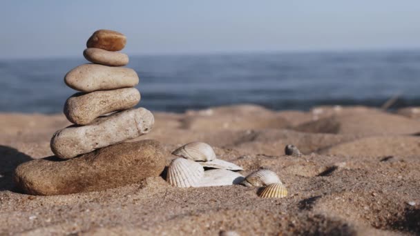 夕暮れ時の海辺の石塔 ビーチでバランスのとれた小石のスタックのクローズアップ 夏休みの瞑想のための石のピラミッド — ストック動画