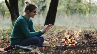 Ilık yeşil kazaklı beyaz kadın, güz mevsiminde, akşam şöminenin yanında oturuyor..