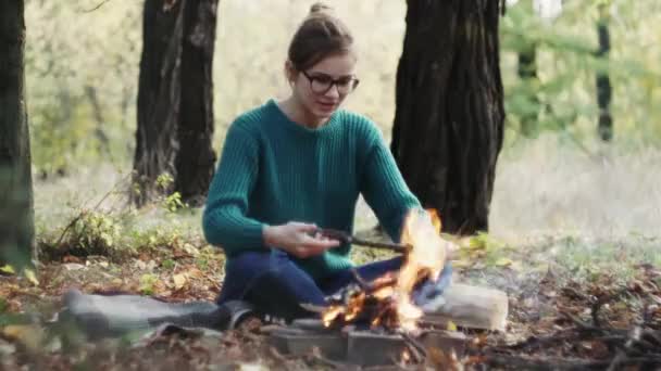 Junge Kaukasische Frau Sitzt Bei Kaltem Sonnenuntergang Lagerfeuer Und Wärmt — Stockvideo
