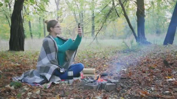年轻的高加索女人坐在森林里篝火边试图捕捉手机信号 — 图库视频影像