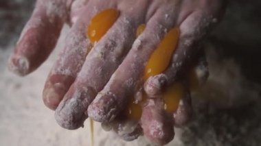 Şef hamuru yoğurmak için yumurta sarısını kırıyor. Yakın plan..