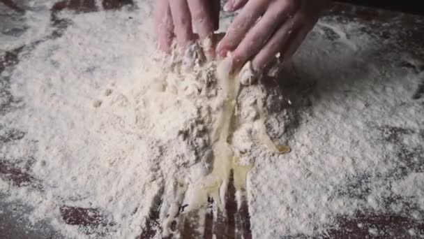 Baker pétrissant la pâte dans la farine sur la table. Procédé de mélange de farine avec oeuf et pâte à pétrir.